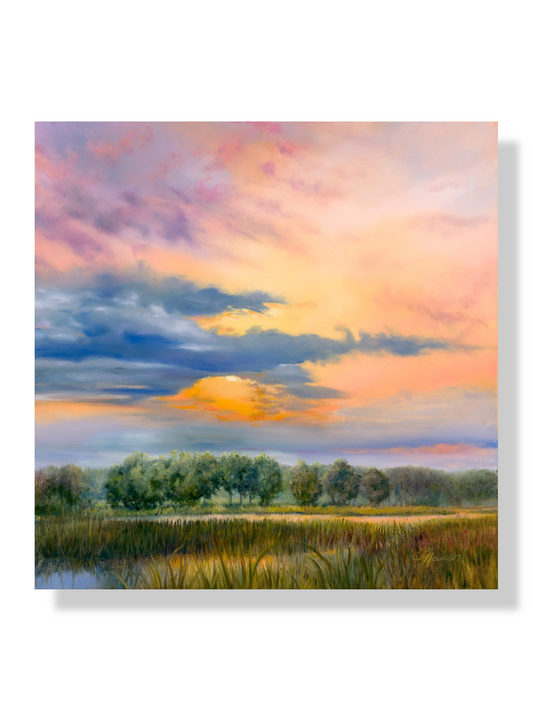 Orange colored sky filled with clouds with the sun peeking through shining on the wetland and trees below.